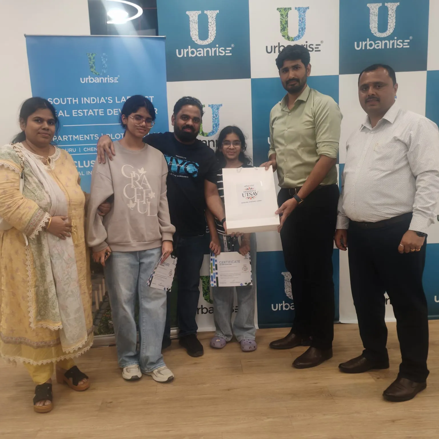 A family holding their Property Utsav bag and certificates